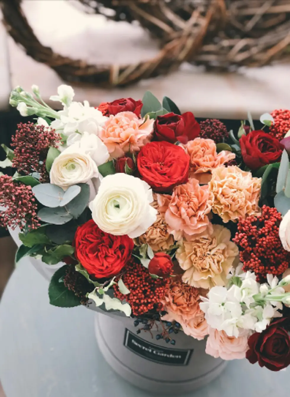 A box arrangement of red, cream and peach flowers