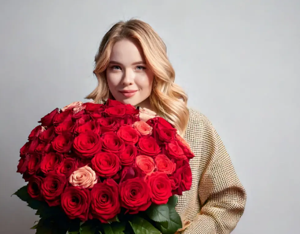 A woman holding a large bunch of red roses